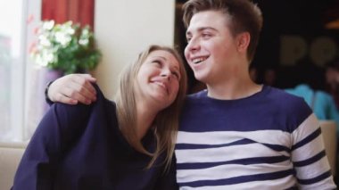 Genç birbirlerine kucaklayan kafe, masada oturan çift. Genç adam alnına kız öpüşme. Slowmotion.