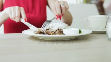 Kırmızı elbiseli tatlı meyveli turta çatal ve bıçak kullanarak restoranda yemek tanınmaz kız. Slowmotion atış.
