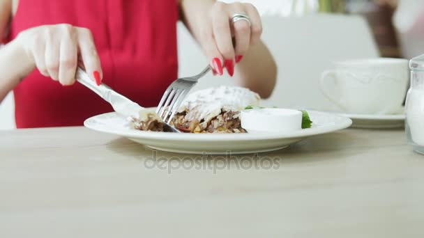 Unerkennbares Mädchen in rotem Kleid, das im Restaurant mit Gabel und Messer Dessertstrudel isst. Zeitlupenschuss. — Stockvideo