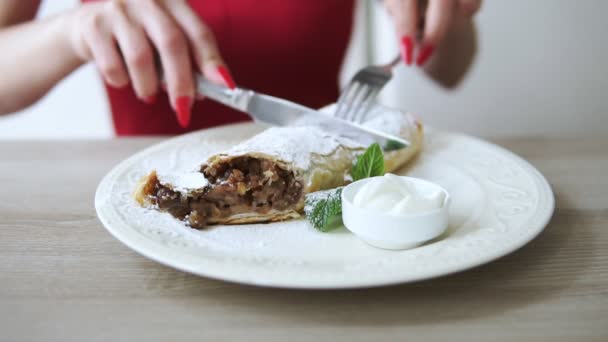 Oigenkännlig flicka i röd klänning äta efterrätt strudel på restaurangen med gaffel och kniv. Slowmotion skott. — Stockvideo