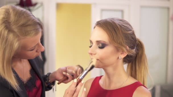 Maquillaje artista utilizando cepillo grande para aplicar polvo facial y acabado maquillaje. Salón de belleza. Disparo en cámara lenta — Vídeos de Stock