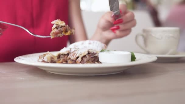 Nie do poznania dziewczynka w czerwonej sukience jedzenia deser strudel restauracji za pomocą widelca i noża. Piękny biały kubek z kawą na stole. Slowmotion strzał. — Wideo stockowe