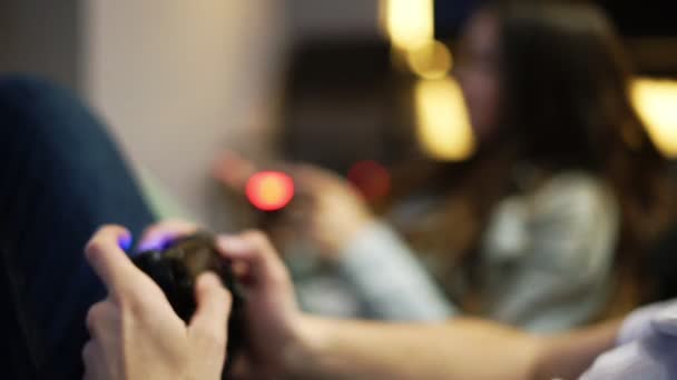 Giovane coppia che gioca ai videogiochi a casa. Uomo explayning come giocare e utilizzare il controller di gioco. Xbox e Playstation. Controllore di gioco wireless. Colpo di rallentamento — Video Stock