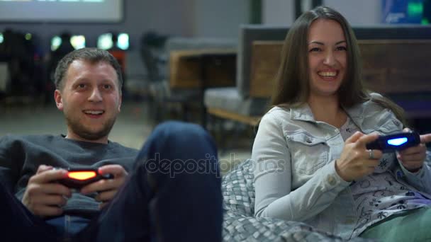 Młoda para w domu gry gry wideo. Człowiek explayning jak grać i użyć kontrolera gier. Xbox i Playstation. Bezprzewodowy kontroler gier. Slowmotion strzał — Wideo stockowe