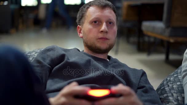 Νεαρό ζευγάρι παίζει βίντεο παιχνίδι στο σπίτι. Γυρίσματα και τον έλεγχο χρησιμοποιώντας το χειριστήριο παιχνιδιού. Xbox και Playstation. Ασύρματο controler παιχνίδι. Slowmotion βολή — Αρχείο Βίντεο