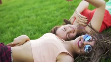 Yaz yaşam tarzı güzel bir gün, parlak güneş gözlüğü takıyor zevk çimenlerin üzerinde döşeme iki hipster kadın portresi. En iyi arkadaşlar kızlar eğleniyor, sevinç. Slowmotion atış