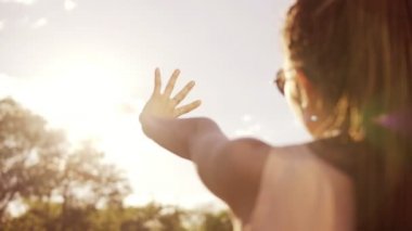 Closeup arkadan görünüm bir kadının güneşe bakarak ve kendini güneşin eliyle kimden saklanıyor. Genç kadın bir güneş ile oynarken dreads ile. Slowmotion atış.