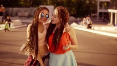 Boş yolda yürürken ve yaz aylarında konuşurken dreads ile iki mutlu kadın. Gülme, sarılma ve parlak güneşli bir günde sırasında birbirlerini öpmeye iki hippi kız. Slowmotion atış.