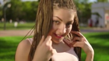 Genç güzel kız dreads bir parkta dans ile. Müzik ve dans sırasında güneşli bir gün güzel bir kadın. Slowmotion atış.