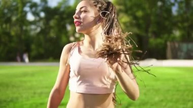 Genç güzel kız dreads bir parkta dans ile. Müzik ve güneşli bir gün boyunca dans kot pantolon güzel bir kadın. Slowmotion atış.