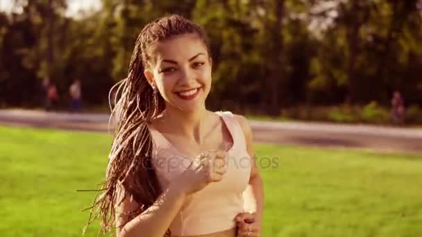 Długie włosy kobieta z dredy w parku i obracając głowę wokół gry z jej dready, patrząc w aparacie. Slowmotion strzał — Wideo stockowe