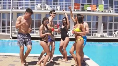 Mutlu genç neşeli arkadaşlar bikini ve mayo dans, kokteyler içme ve Villa da havuzda eğleniyor. Yaz aylarında havuz partisi. Slowmotion atış