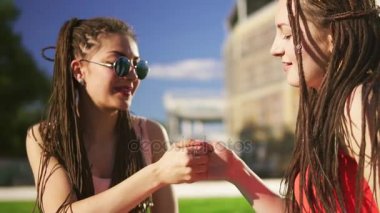 Mutlu kadın yaz Park çimenlerin üzerinde oturan dreads ile. Söz ve açık havada eğleniyor oynayan genç arkadaşlar. Slowmotion atış