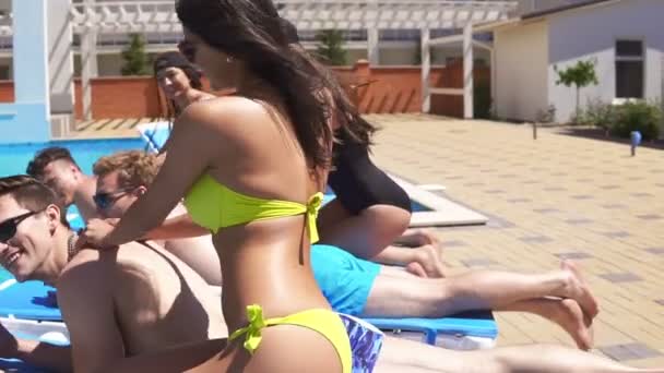 Trois hommes recevant des massages de jolies jeunes filles en bikini allongées sur des entraîneurs au bord de la piscine dans une belle villa et buvant de la bière. Coup de ralenti . — Video