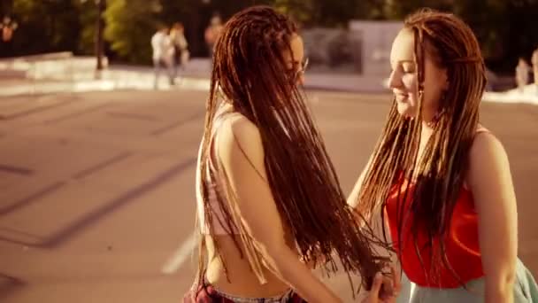 Dos mujeres felices con temores caminando por el camino vacío y hablando en verano. Dos chicas hipster riendo y bailando durante un día soleado brillante. Disparo en cámara lenta . — Vídeos de Stock