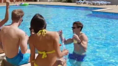 Mutlu grup kokteyler ile takılmak ve yaz aylarında havuz kenarında sohbet ve dans genç arkadaşlar. Havuz partisi. Slowmotion atış