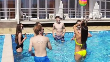 Grup genç arkadaşlar yüzme havuzunda voleybolu top oynarken. Yaz aylarında havuz partisi. Slowmotion atış