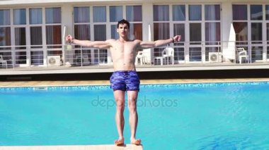 Yüzme Havuzu düşen Yüzme şortu giymiş genç atletik adam. Slowmotion atış.
