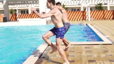Koşu ve Yüzme Havuzu etrafında atlama swimshorts iki genç atletik erkek. Slowmotion atış.