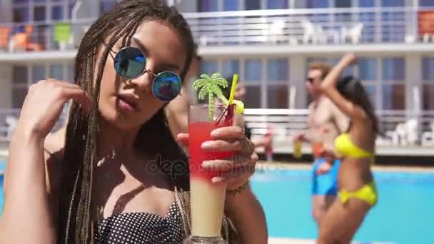 Menina bonita nova com dreads e óculos de sol vindo de roupa para câmera enquanto dança na festa da piscina. Summertime Slowmotion shot — Vídeo de Stock