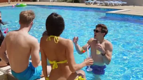 Glada grupp unga vänner umgås med coctails och chattar på sidan av poolen på sommaren och dans. Poolparty. Slowmotion skott — Stockvideo