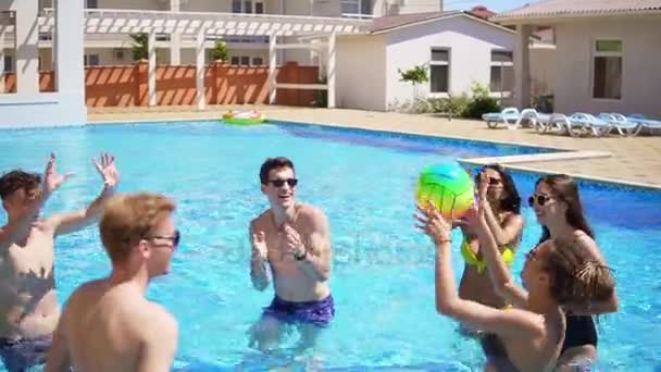 Gruppen av unga vänner som spelar volleyboll i poolen. Sommaren poolparty. Slowmotion skott — Stockvideo