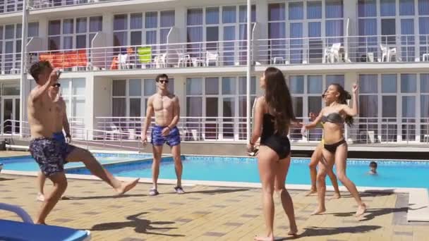 Grupo de jóvenes amigos jugando voleibol en la piscina. Fiesta de verano en la piscina. Disparo en cámara lenta — Vídeo de stock