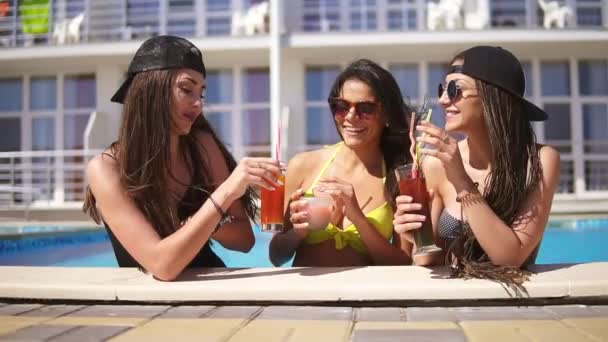 Meninas bonitas em óculos de sol bebendo coquetéis relaxando na piscina. Festa da piscina no Verão. Tiro em câmara lenta — Vídeo de Stock