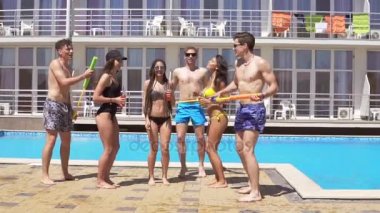 Dans ve having fun havuzda mutlu genç neşeli arkadaşları. Yaz aylarında havuz su silahlarla parti. Slowmotion atış
