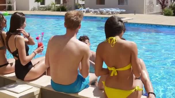 Счастливая группа молодых друзей тусуется с коктейлями и болтает у бассейна в летнее время и танцует. Вечеринка. Слоумоушн — стоковое видео