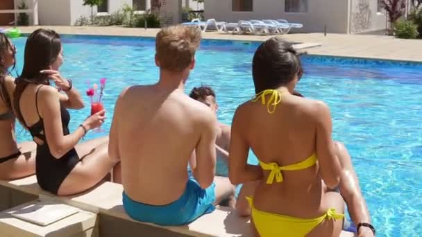 Feliz grupo de jóvenes amigos pasando el rato con cócteles y charlando al lado de la piscina en el verano y bailando. Fiesta en la piscina. Disparo en cámara lenta — Vídeo de stock