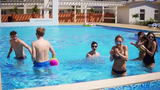 Grupa młodych przyjaciół, pograć w siatkówkę w basenie. Impreza na basenie latem. Slowmotion strzał — Wideo stockowe