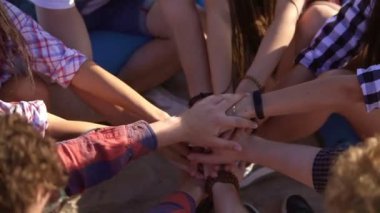 Birlikte united ve kaldırdı daha fazla el closeup görünümü. Takım çalışması ve dostluk kavramı. Bir yaz akşamı kumsalda easychairs üzerinde oturan arkadaş grubu. Slowmotion atış