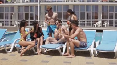 Kokteyl içme ve eğlenmek güzel genç arkadaşlar grup yüzme havuzunun kenarında oturuyor. 4 k'dan fazla vurdu