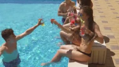 Mutlu genç arkadaşlar kokteyler ile takılmak ve yaz aylarında havuz kenarında sohbet, kokteyl içme ve tezahürat yapıyor. Havuz partisi. 4 k'dan fazla vurdu