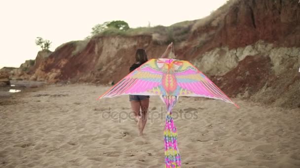 Joven mujer hipster liberando colorido cometa en la playa por la noche. Disparo en cámara lenta — Vídeos de Stock