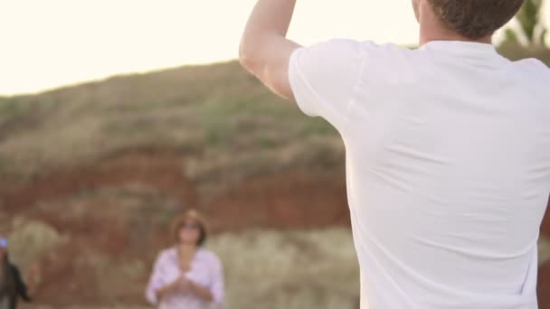 Joyeux jeunes amis jouant au volley-ball sur la plage au bord de la mer le soir. Vacances actives. Coup de ralenti — Video