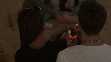 Grup genç arkadaşlar sahilde, şömine başında oturan marsh mallows ızgara. Slowmotion atış