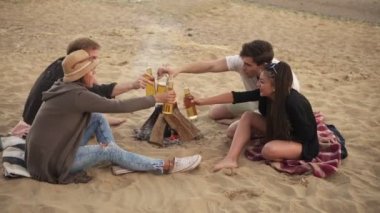 Bira şişeleri ile toasting ve şerefe bira 4 k ile söyleyerek bir yaz gününde parti bir plaj olan gençlerin grup