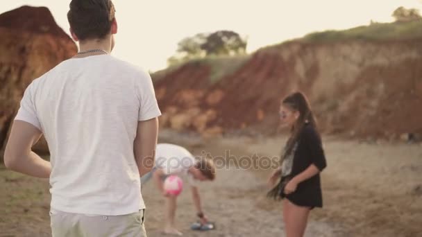 Jóvenes amigos jugando voleibol en la playa junto al mar durante el atardecer. Trabajo en equipo. Disparo en 4k — Vídeo de stock