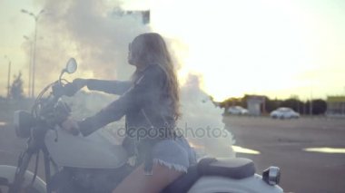 Bir lastik tükenmişlik yapıyor bir motosiklet üzerinde oturan bir genç bayan. Duman motosiklet koltukta oturan kısa filmlerde çok kadın motorcu