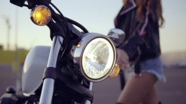 Geliyor ve motosiklet üzerinde getting şortlu kadın bir bisikletçinin portresi. Genç seksi kıvırcık kadın helikopter üzerinde güneş gözlüğü