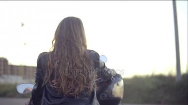 Motosiklet koltukta oturan uzun saçlı kadın bir bisikletçinin arkadan görünüm. Genç kıvırcık kadın helikopter üzerinde kapat