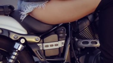 Bir kadının geri şortlu ve siyah çizmeler bisiklet üzerinde otururken bacaklarda kapatmak