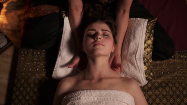 Молодая женщина с закрытыми глазами делает тайский массаж шеи и плеч в спа-салоне неузнаваемым женским массажером. Здравоохранение и спа. Слоумоушн — стоковое видео