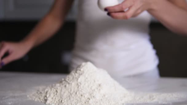 Female hands break the egg into flour on the kitchen table. Slowmotion shot — Stock Video