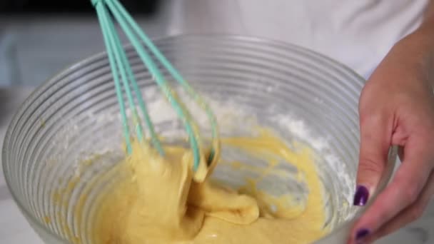 Vista de cerca de las manos femeninas preparando la masa mezclando ingredientes usando batidor en la cocina. Comida casera. Disparo en cámara lenta — Vídeo de stock