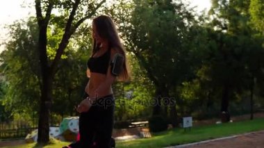 Kısa spor top ve kol bandı spor çantası parkta yürüyüş güzel esmer kadın. Sabah egzersiz sağlıklı spor kadın uygun. Slowmotion atış