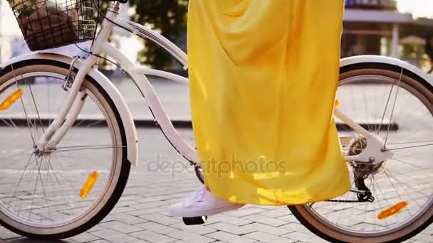 Closeup view of a white city bicycles wheels spinning. Citybike with a bell, basket and flowers. Unrecognizable woman riding a city bicycle early in the morning. Steadicam shot. Slowmotion — Stock Video