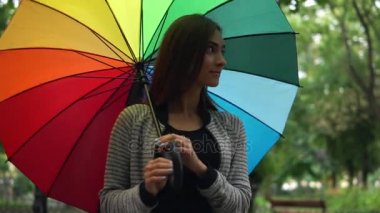 Yürüyüş ve onun renkli şemsiye yağmurlu bir gün şehir parkında iplik genç güzel mutlu bir kadın portresi